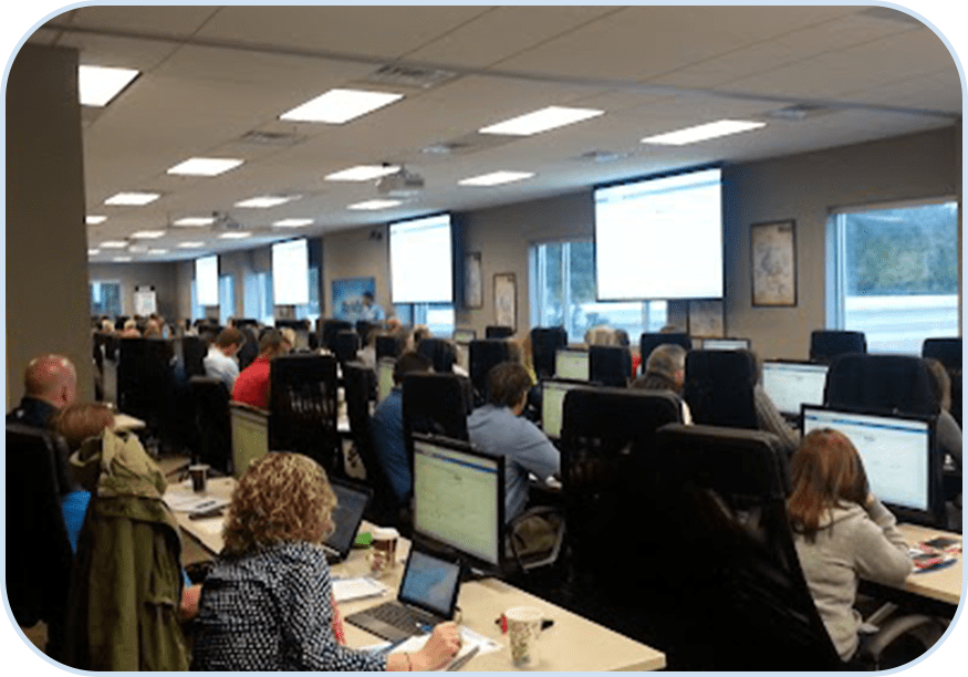 A group of people sitting at tables with computers.