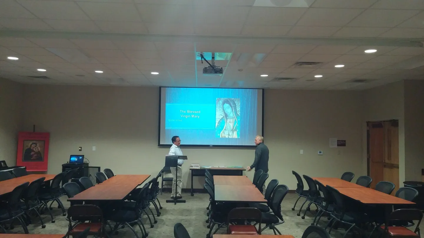 Two men standing in front of a projector screen.