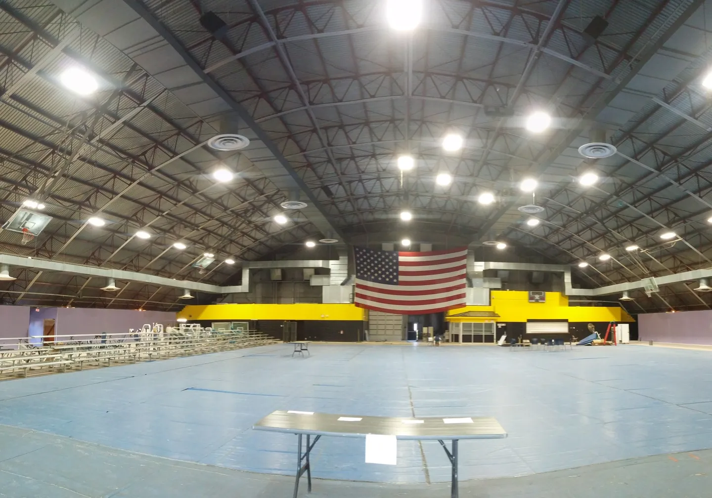 A large indoor arena with tables and american flag.