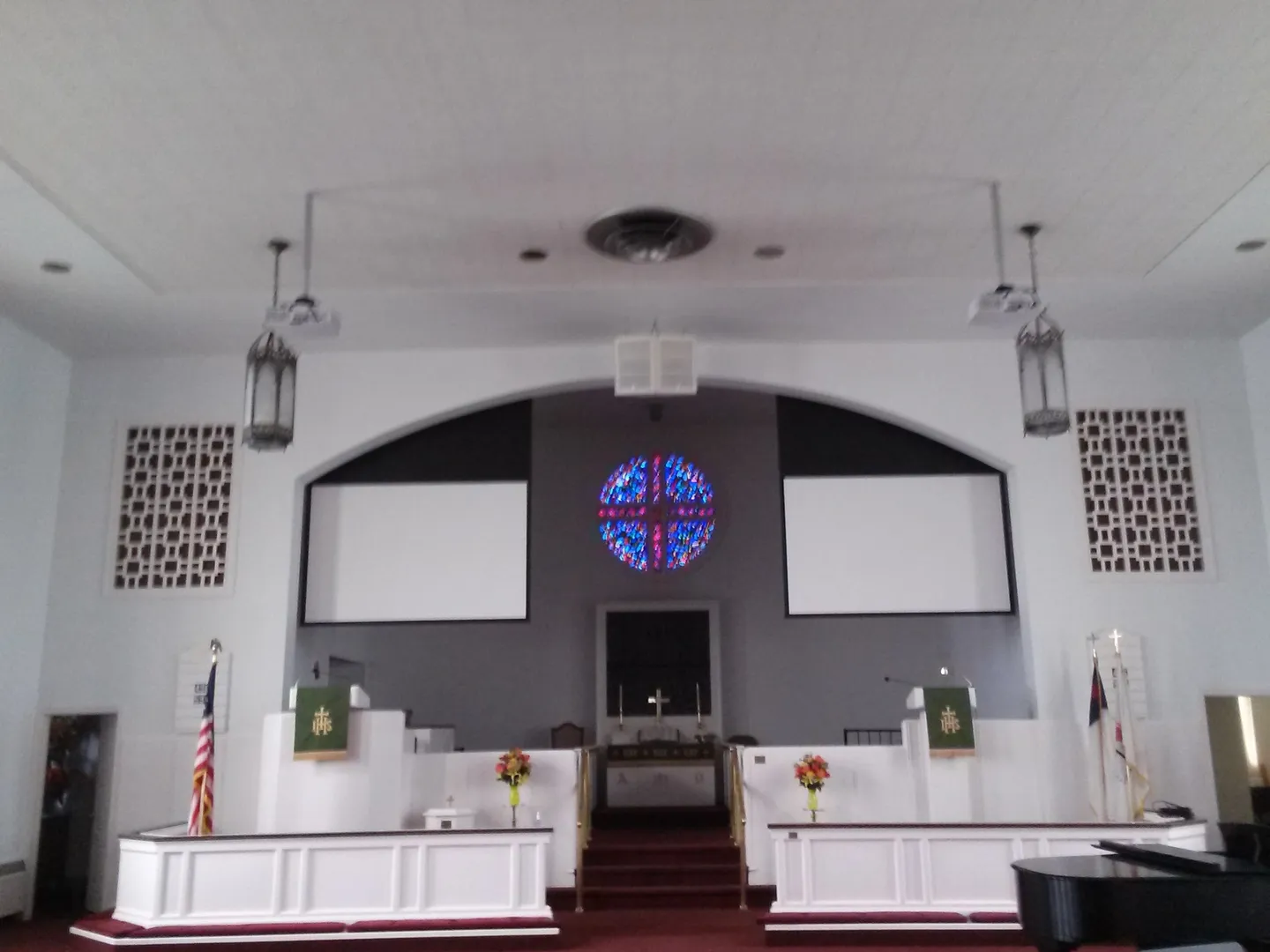 A church with two large screens and a cross on the wall.