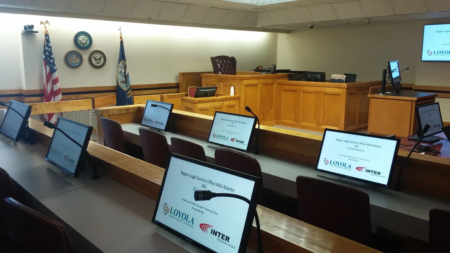 A courtroom with laptops and chairs in front of the judge.