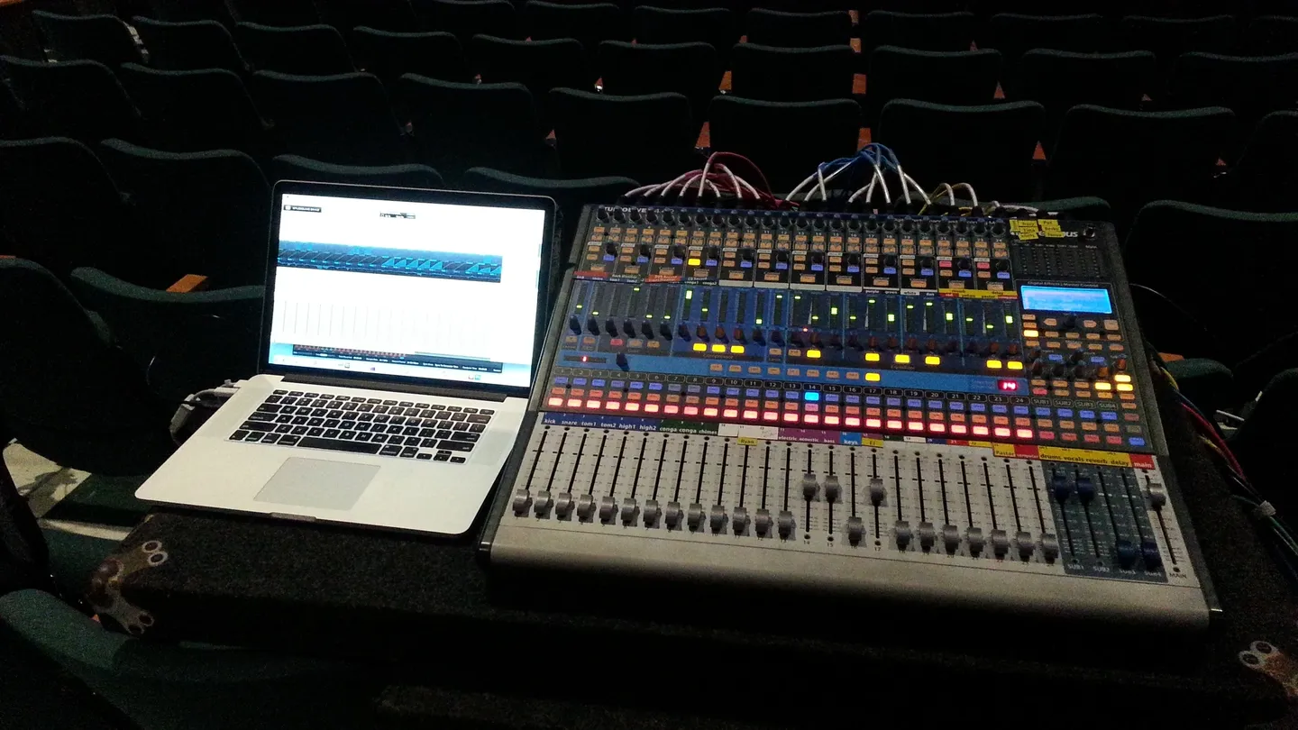 A laptop and sound board in front of an empty auditorium.