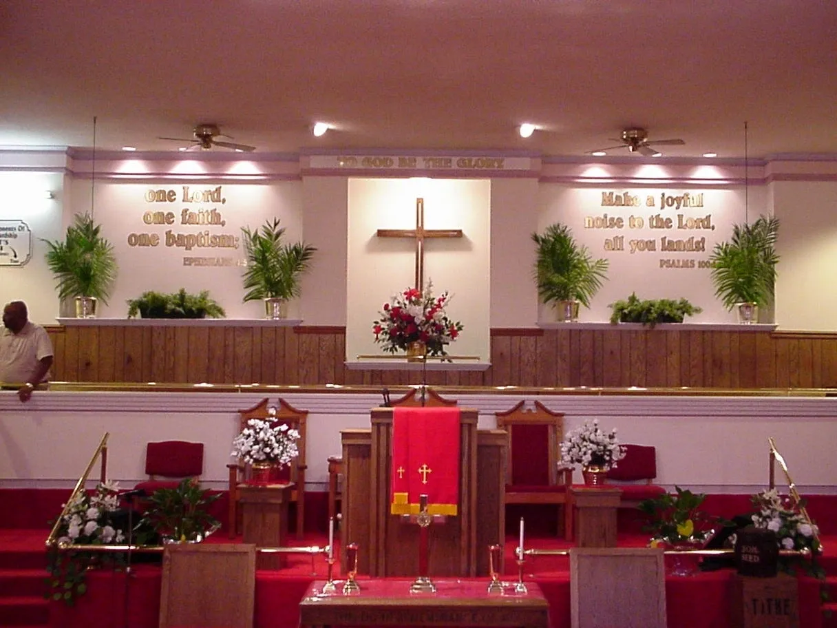 A church with red chairs and a cross on the wall
