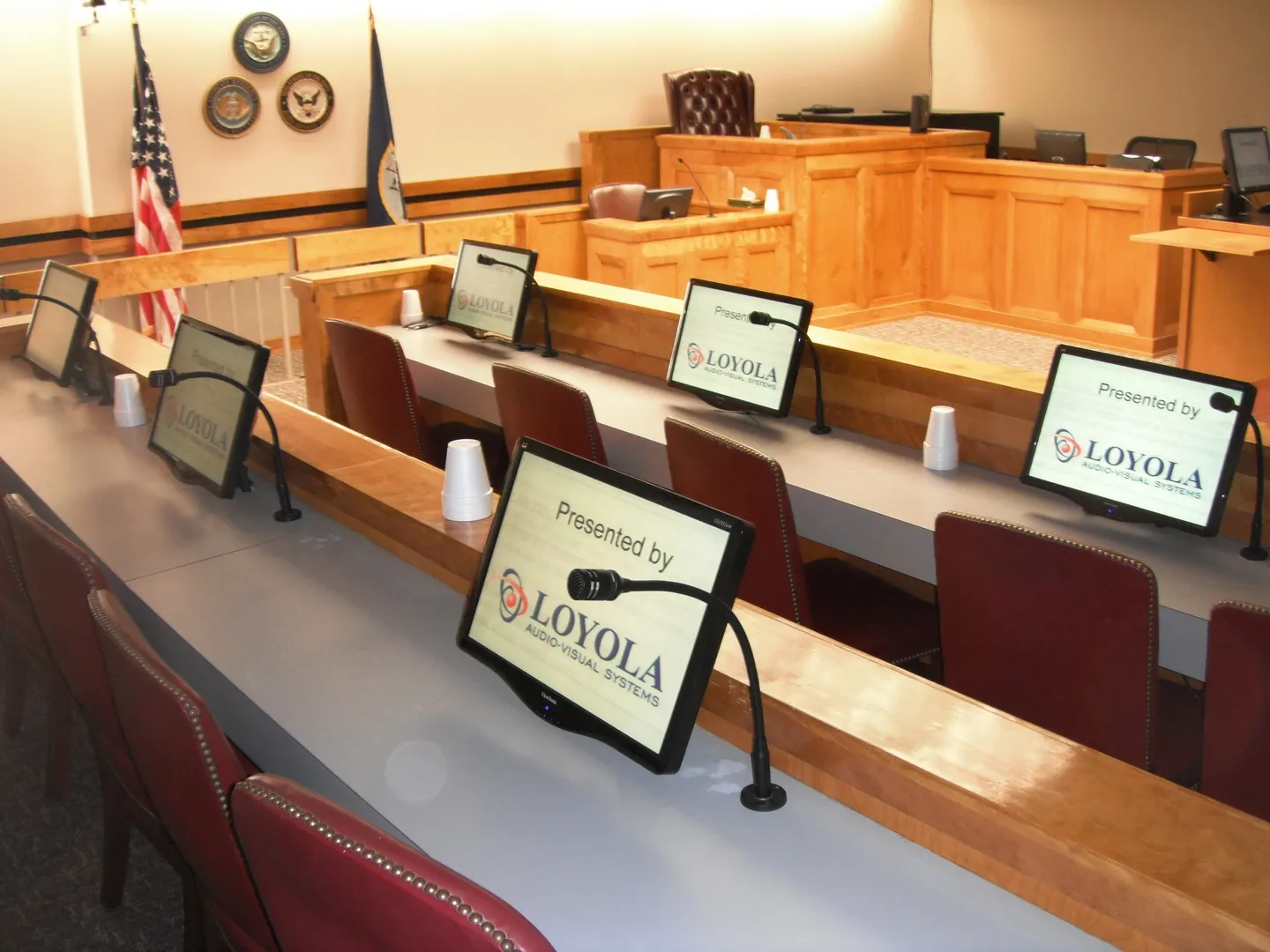 A courtroom with a tablet and microphone on the desk.