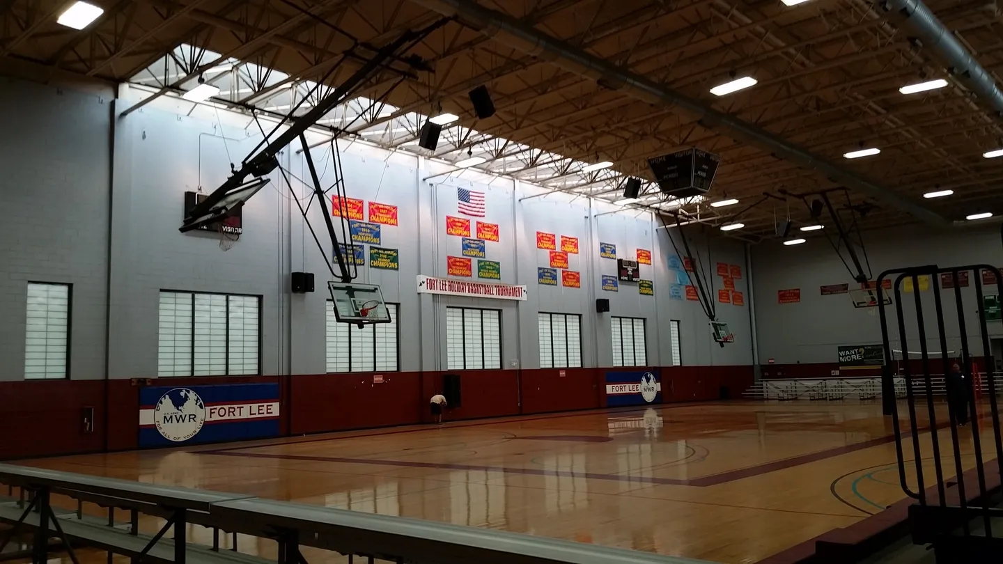 A gym with many basketball hoops and banners on the wall.