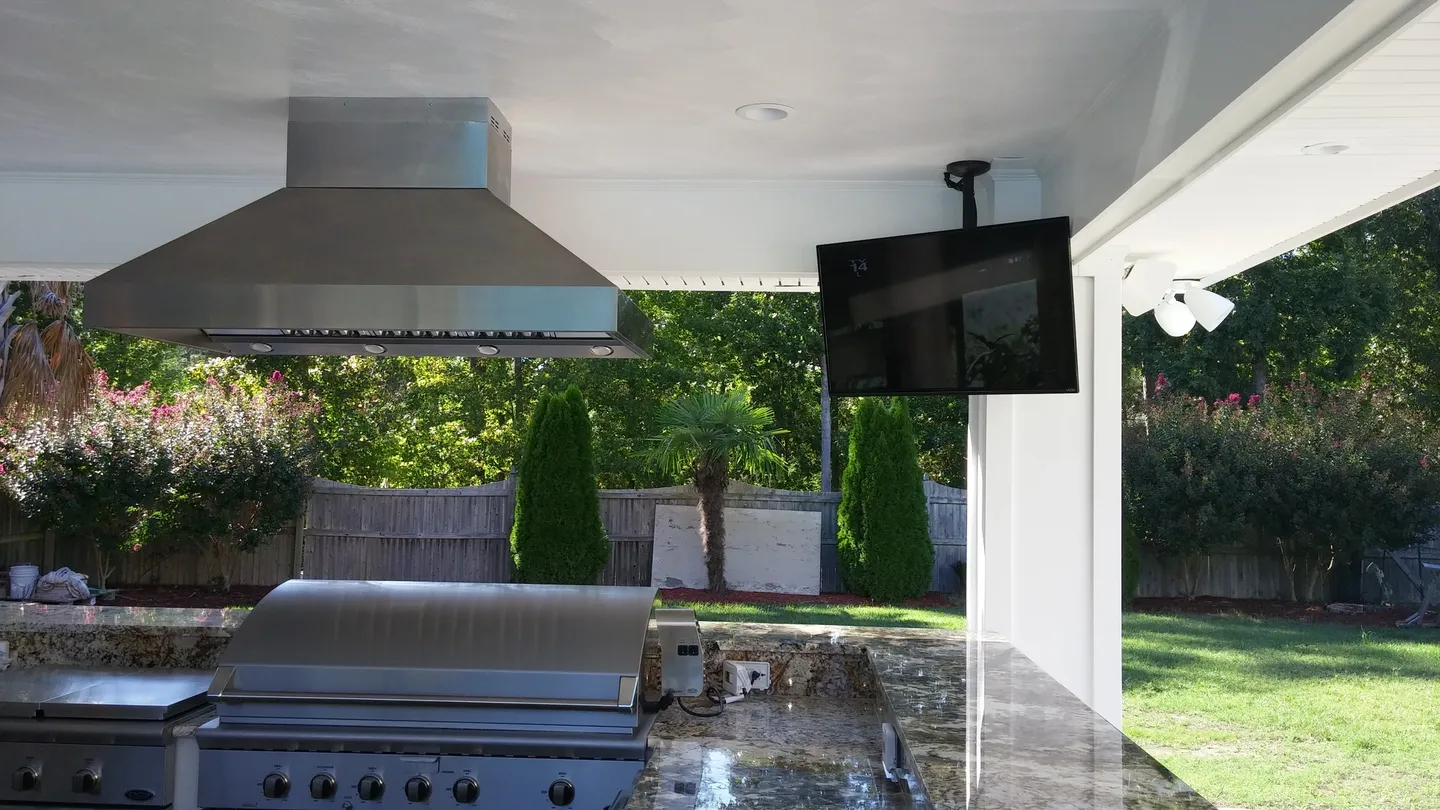 A television mounted on the wall of an outdoor kitchen.